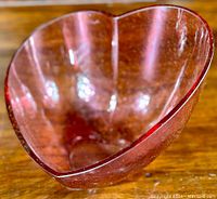Heart shaped pink and clear glass bowl with textured surface, angled side view
