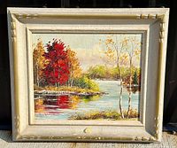Full front view of the framed oil painting showing the spring scene on a river with red and yellow trees.