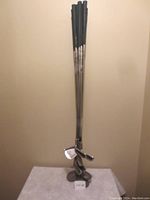 Photo showing seven Spalding Pro Flite Gold irons and three woods standing upright with black grips and metal shafts and heads.