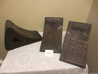 Photo of 3 heavy duty wheel chocks arranged on a table, showing their wedge shape and triangular cutouts.