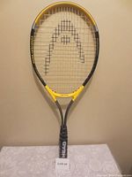 Front view of the Head aluminum tennis racket with yellow and grey frame and logo on strings.