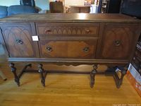 Front view of the antique buffet sideboard showing carved wood doors, decorative drawer pulls, and overall structure.