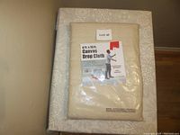 Folded canvas drop cloth in original packaging, label visible showing size 4ft by 15ft and branding as canvas drop cloth.