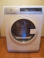 Front view of Electrolux front load steam dryer showing large circular glass door and control panel above.