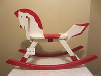 Full side view of a vintage hand-crafted wooden rocking horse painted white and red, showing size and condition.