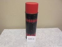 Closed vintage thermos standing upright, displaying black body with red diamond patterns and red lid