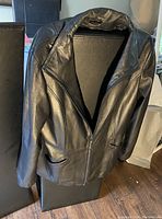 Black Danier leather jacket hanging, showing front and sleeve detail.