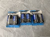 Three unopened packages of Panasonic Double D batteries, each containing two batteries. Batteries are black and blue with Panasonic branding and specification text.