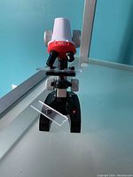 Front angle photo of kids microscope in black/red plastic with 400x magnification label, including 2 glass slides, one placed on microscope stage.
