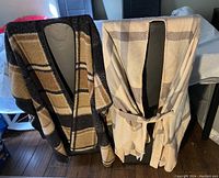 Two ladies poncho capes displayed on mannequins, one with a plaid pattern and the other with a matching belt.