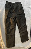 Photo of a pair of black youth large snow pants 12/14 size laid flat showing front side with elastic waistband and zipper pockets.