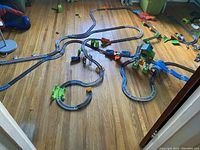 Overview of the three assembled Thomas the Train plastic track sets on hardwood floor showing track layout and accessories