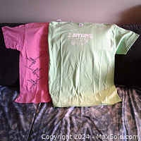 Two t-shirts laid flat: light green with seal print and pink with bird prints
