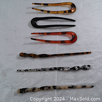 Six hair accessories laid out on white background including three large U-shaped hair pins and three twisted hair chopsticks with leopard/tortoiseshell patterns, glossy finish.