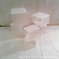 Six acrylic display stands arranged showing different heights and L-shape design with frosted translucent finish.