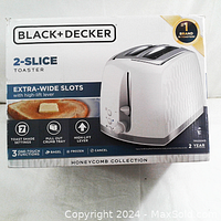 Boxed Black and Decker 2-slice toaster, showing front of the retail packaging with brand, model details, and features