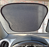 Dark mesh sun shade attached inside car window, black trim, flexible frame
