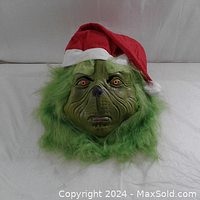 Front view of the green Grinch latex mask with Santa hat showing facial details and fur surrounding face.