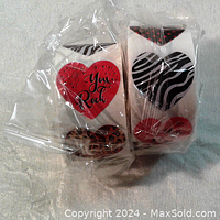 Two rolls of heart stickers sealed in plastic, showing red hearts with text and black and white zebra pattern hearts.