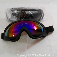 Pair of ski goggles with rainbow reflective lens and black strap, one pair still in sealed packaging behind.