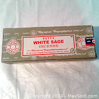 Photo showing top view of the sealed olive green box with Satya White Sage label and branding.