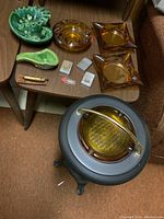View of all ashtrays, pipe rest, lighters on a small table with black metal ashtray stand in front