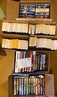 Seven boxes packed with Clive Cussler novels in hardcover and paperbacks, about 100 books total.