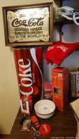Framed vintage Coca-Cola mirror, tall wastepaper can, red scarf, small bowl, boxed 40-piece can puzzle, small Coca-Cola deliveries truck toy on shelf.