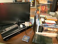 Photo showing RCA 18 inch TV monitor, Toshiba DVD player with remote, and a tray filled with DVDs including Lord of the Rings and others.
