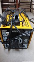 Front view of yellow Deca welding machine with cables attached