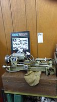 Front view of Unimat lathe on wooden storage case with manual propped behind