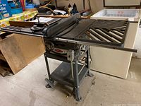 Side angle showing full Rockwell tilting arbor saw with metal table wings, sturdy frame on wheels.