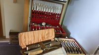 Complete silver plated dinnerware set with knives, forks, spoons, and assorted serving pieces in red felt-lined case with carving set and cutting utensils in front.