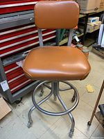 Front view of shop stool showing padded seat, backrest, frame and casters