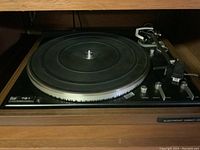 Front view of the turntable showing platter, tonearm and wooden housing.
