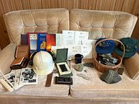 Full lot overview showing hard hat, rock samples, books, maps, and various instruments on a beige couch