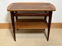 Front view of the walnut side table showing top tier and lower shelf with tapered legs.