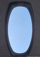 Full frontal view of the vintage brown molded oval mirror showing the frame detail and clear reflective glass.