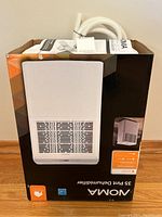 Front view of the Noma 35 Pint Dehumidifier in its original box with visible product image and included manual and hose on top.