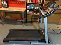 Full view of the folded treadmill in basement workshop area, showing the overall size and design of the equipment.
