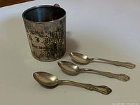 Mug and three spoons arranged on white background