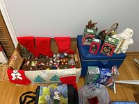 Overview of red furry stockings, assorted ornaments in a festive box, and additional packed items including boxed lights.