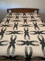 Quilt laid flat on queen-sized bed showing detailed patchwork and scalloped edge detail.