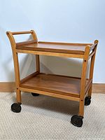 Photo showing front and side view of the vintage tea trolley with beechwood frame and teak trays on caster wheels.
