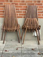 Two folding chairs stacked, showing folded view and overall condition leaning against brick wall