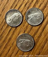 Obverse side of three 1967 Canadian silver 25 cent cougar coins showing the cougar design and date markings