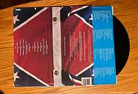 Back cover of album with tracklist and credits featuring Confederate flag design and vinyl record partially visible.