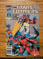 Front cover of The Transformers comic issue #12 depicting Optimus Prime and other Autobots in action.