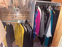 Wide view of clothing hanging on two closet rods including jackets, skirts, fur coats, and other items.