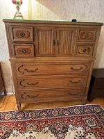 Front view of entire wood dresser showing top glass, four small upper drawers behind doors, three lower drawers and bracket feet.